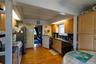 Wood-finish flooring, exposed ceiling beams, light wood-finish cabinetry, black countertops, and a stainless steel sink