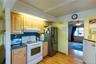 Kitchen with wood-finish flooring, natural wood cabinetry, blue countertops, and stainless steel appliances