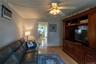 Hardwood-style flooring with a dark wood built-in media cabinet, crown molding, and a ceiling fan with integrated lighting