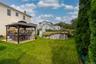 Expansive green lawn featuring a covered patio with a dark metal gazebo and an above-ground pool