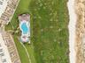 From above, the coastline reveals itself — pool, palms, and the ocean's edge
