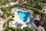 Resort-style pool area with a freeform swimming pool, integrated spa, paver decking, lush landscaping, and cabana structure