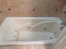 Built-in soaking tub with multiple jets, integrated bath faucet, and surrounding tile work with decorative accents