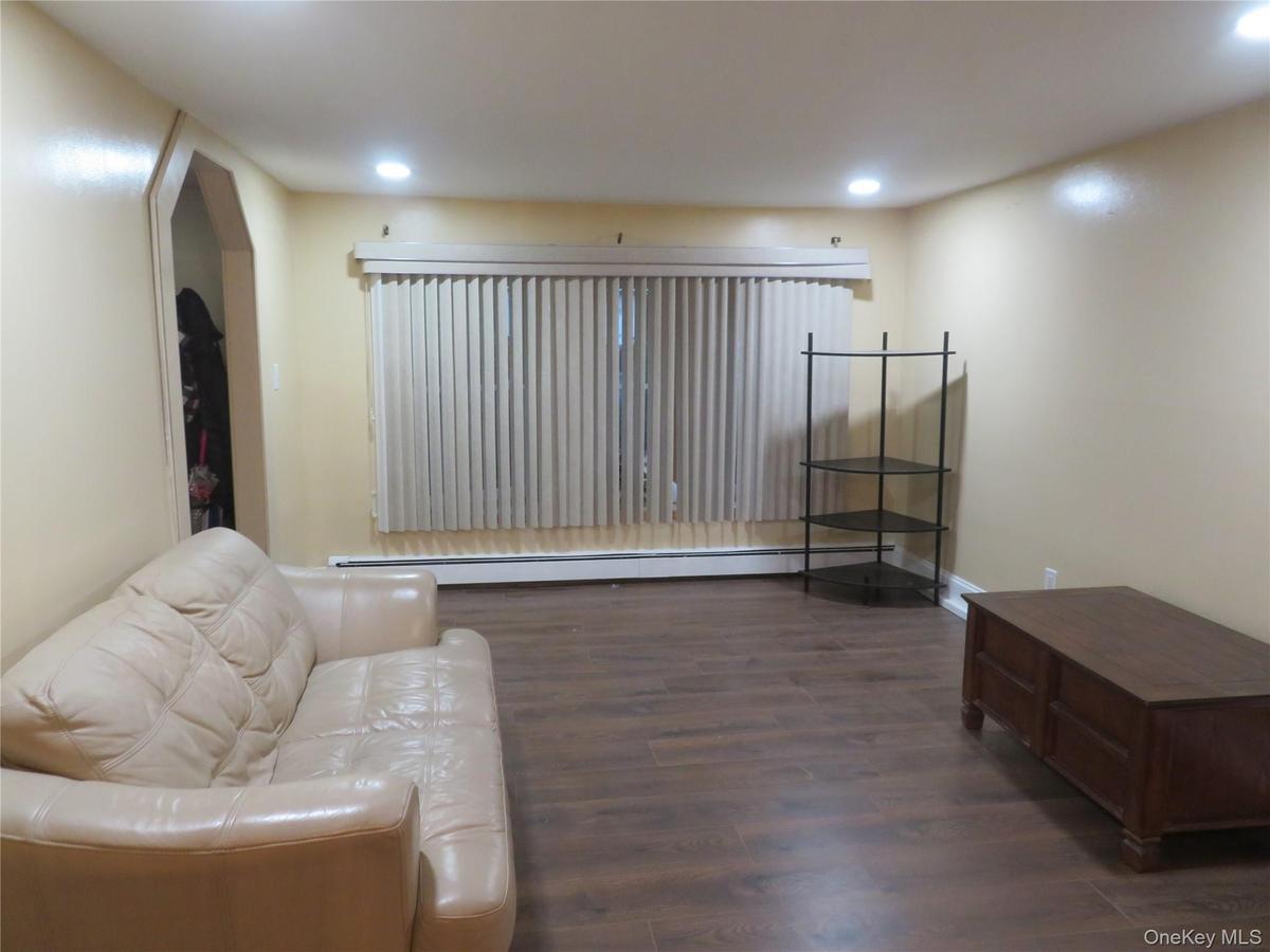 Recessed ceiling lighting, wood-finish flooring, and a large window with vertical blinds