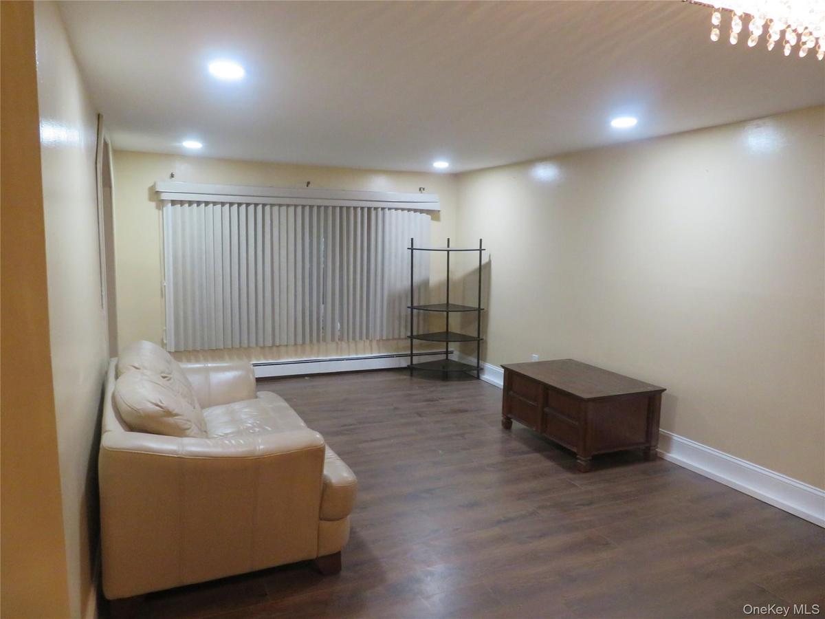 Recessed lighting, wood-finish flooring, vertical blinds, and a built-in baseboard heater