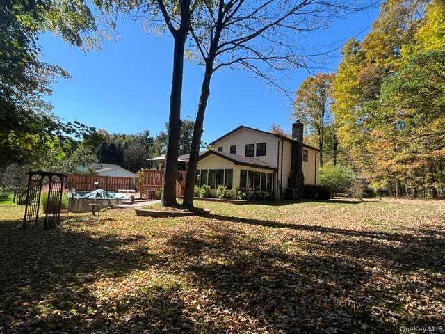 Expansive backyard with a manicured lawn and mature trees,  above ground pool and featuring a multi-level wood deck and a stone chimney