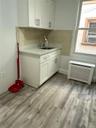 White shaker cabinetry, light-toned backsplash, stainless steel sink with a gooseneck faucet, light-toned countertop, and wood-finish flooring