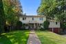 Welcome to 16 Cadillac Drive. Two-story residence with a brick paver walkway, mature trees, and a front lawn.