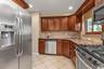 Kitchen featuring wood cabinetry, stainless steel appliances, tile flooring, and granite countertops