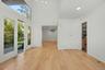 Spacious, light-filled entry foyer with high ceilings, expansive windows, and newly refinished hardwood floors.