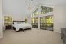 Primary bedroom retreat with soaring cathedral ceilings, expansive windows, and sliding doors to a private deck overlooking the wooded grounds.