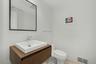 Powder room conveniently located near the office, featuring a floating wood vanity and a vessel sink.