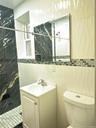 Shower with black and gold-veined tile, mosaic accent border, white wave-patterned wall tile, and a white vanity with an integrated sink