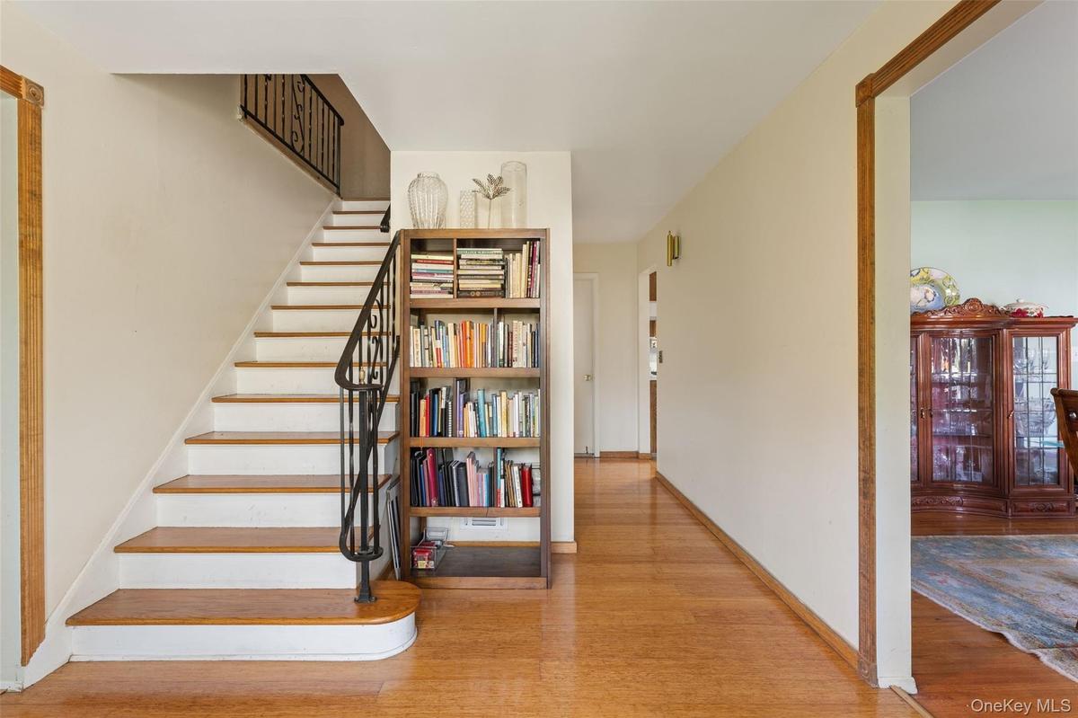 Entryway featuring hardwood flooring and a staircase with wrought iron railing.
