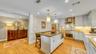 Hardwood flooring, white shaker cabinetry, stainless steel appliances, stone countertops, and recessed lighting