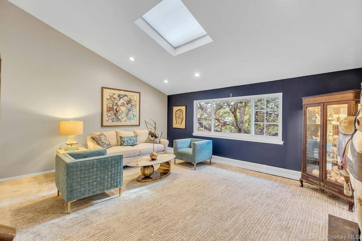Vaulted ceiling with skylight, recessed lighting, and large bay window.