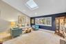 Vaulted ceiling with skylight, recessed lighting, and large bay window.