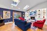 Vaulted ceiling with skylights, wood-finish flooring, built-in shelving, and a gas fireplace