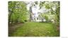 Expansive lawn surrounded by mature trees, featuring a white multi-story residence with multiple windows and a balcony