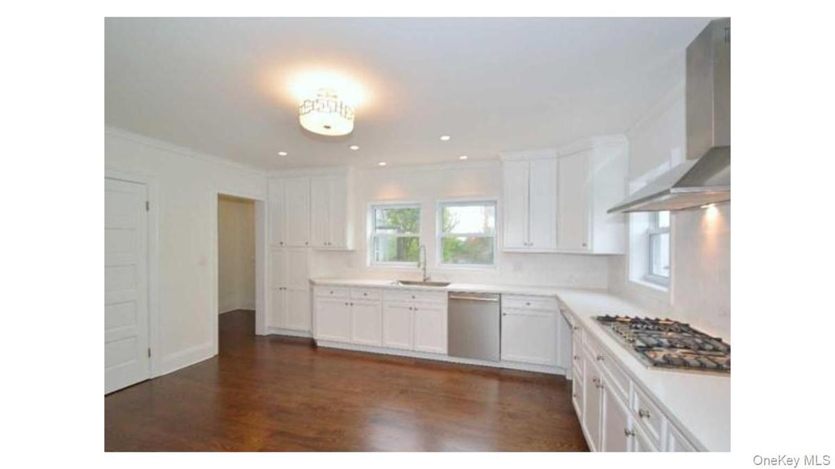 Kitchen featuring white shaker cabinetry, stainless steel appliances, recessed lighting, and wood-finish flooring