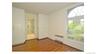 Wood-finish flooring with built-in cabinetry, an arched window, and an en-suite bathroom with a glass-enclosed shower