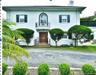 White stucco exterior with black functional shutters, front entry with transom window, second-story Juliet balcony, and paved driveway