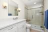 Bathroom on lower level has a stall shower with glass door and seating