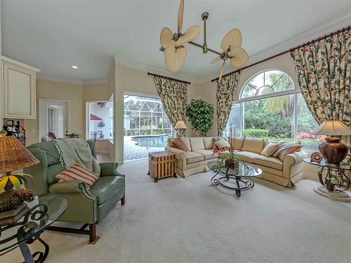 A bright, inviting family room framed by expansive windows and sliding doors that seamlessly connect to the lanai.