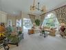A bright, inviting family room framed by expansive windows and sliding doors that seamlessly connect to the lanai.