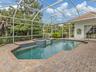Screened lanai surrounded by lush gardens, offering privacy from the fairway.