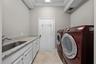 A spacious laundry room with front-load appliances, a utility sink, and plenty of counter and cabinet space.