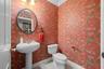 Cheerful patterned wallpaper and a classic pedestal sink bring personality to this bathroom.