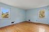 A bright bedroom with hardwood floors and windows overlooking the property.