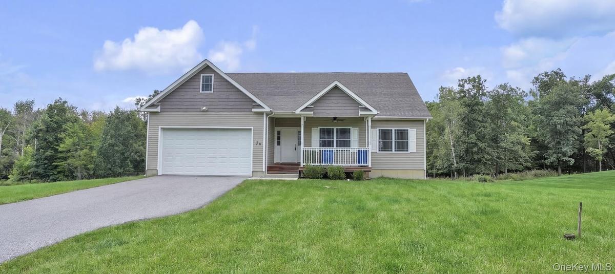 Siding exterior with a covered porch, attached garage, and a paved driveway