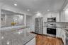 Granite countertops, white shaker cabinetry, stainless steel appliances, wood-finish flooring, and recessed lighting