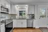 Kitchen featuring white cabinetry, stainless steel appliances, granite countertops, a tiled backsplash, and wood-finish flooring, access to backyard r