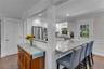 Bright, open-concept kitchen and dining area featuring white cabinetry, stainless steel appliances, quartz countertops, and a large center island with
