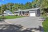 Ranch-style exterior with gray horizontal siding and stone accents. Double wide driveway with access to one car attached garage,