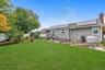 Expansive rear lawn with mature trees and perimeter landscaping