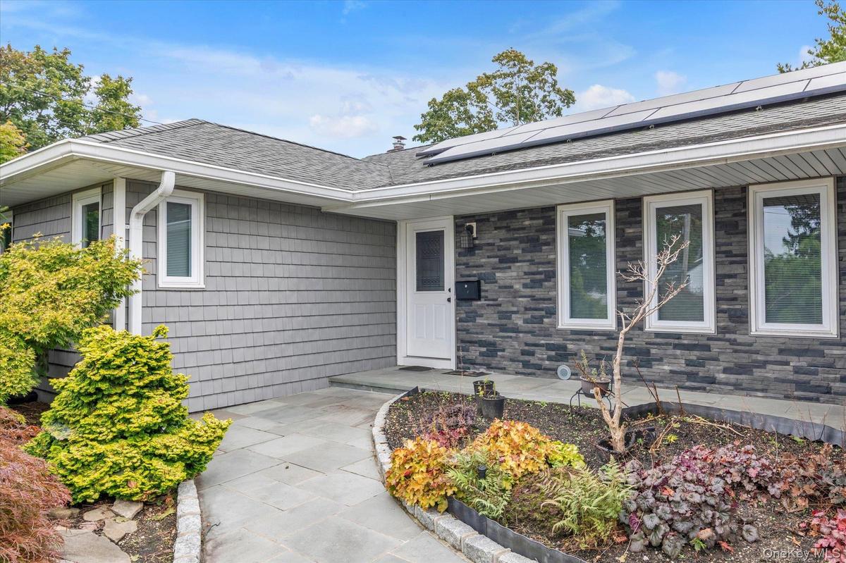 Gray shake siding exterior with dark stone accents, white window frames, and sitting area