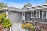 Gray shake siding exterior with dark stone accents, white window frames, and sitting area