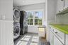 Tile flooring, window with exterior scenery, beadboard wainscoting, white cabinetry, and a bright green countertop
