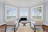 Bay window with water scenery, crown molding, and hardwood flooring