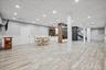 Recessed lighting illuminates the wood-finish flooring, wainscoting, and white trim