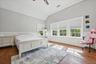 Vaulted ceiling with recessed lighting, wood-finish flooring, white paneled wainscoting, and large windows with cellular shades