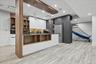 Modern kitchen area featuring light wood-finish flooring, white and charcoal cabinetry, built-in shelving, stainless steel appliances, and recessed li