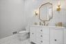 White vanity with gold-tone hardware, white countertop, and gold-tone faucet