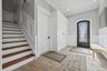 Entryway featuring tile flooring, wainscoting, an ornate arched entry door, a built-in storage cabinet, and a staircase with wood-finish treads