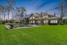 Expansive green lawn with a rectangular swimming pool, a brick exterior residence, a covered patio, and a separate cabana structure