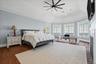 Vaulted ceiling with a contemporary ceiling fan, multiple large windows, wood-finish flooring, and crown molding